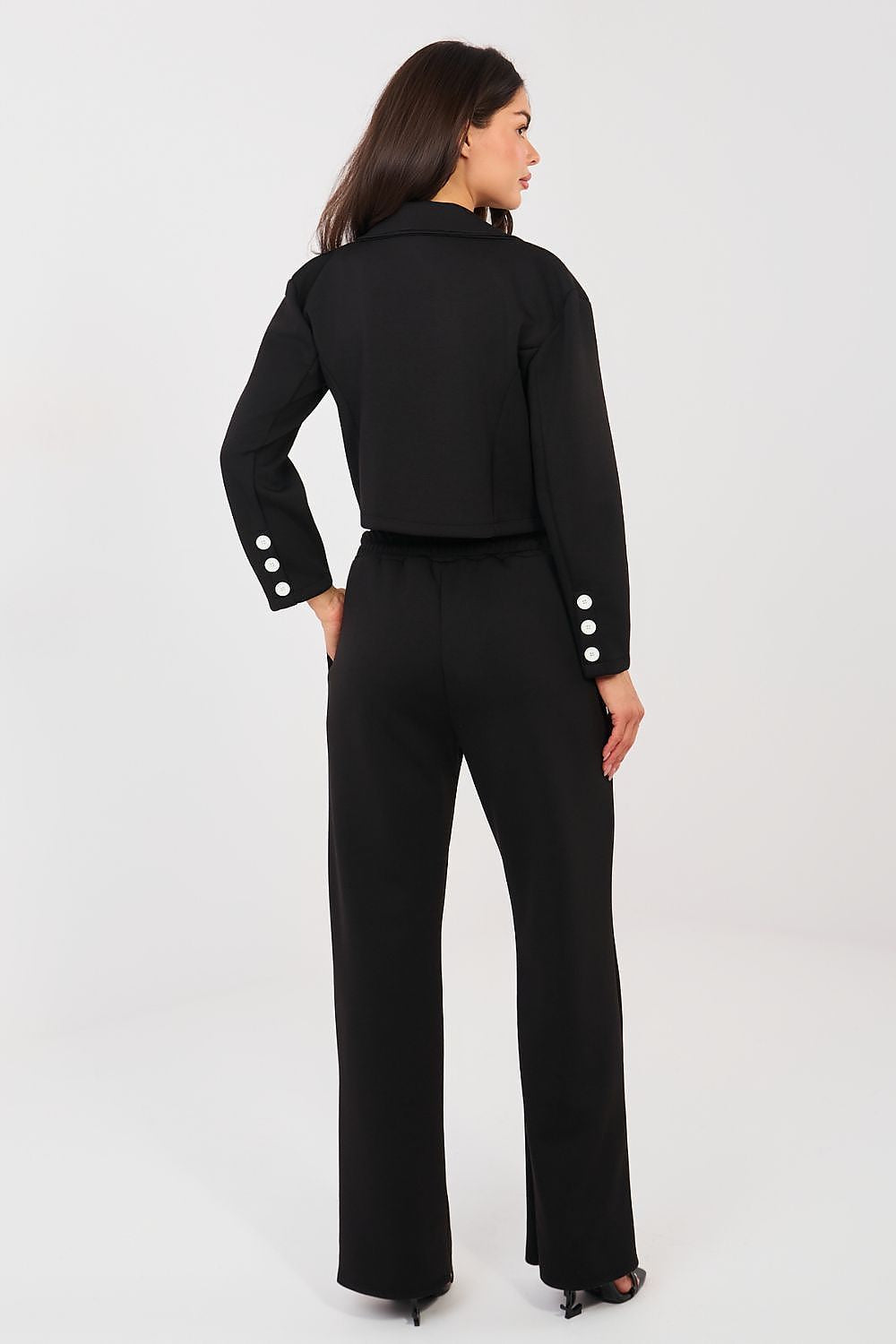 Woman wearing a black outfit with white buttons on a white background