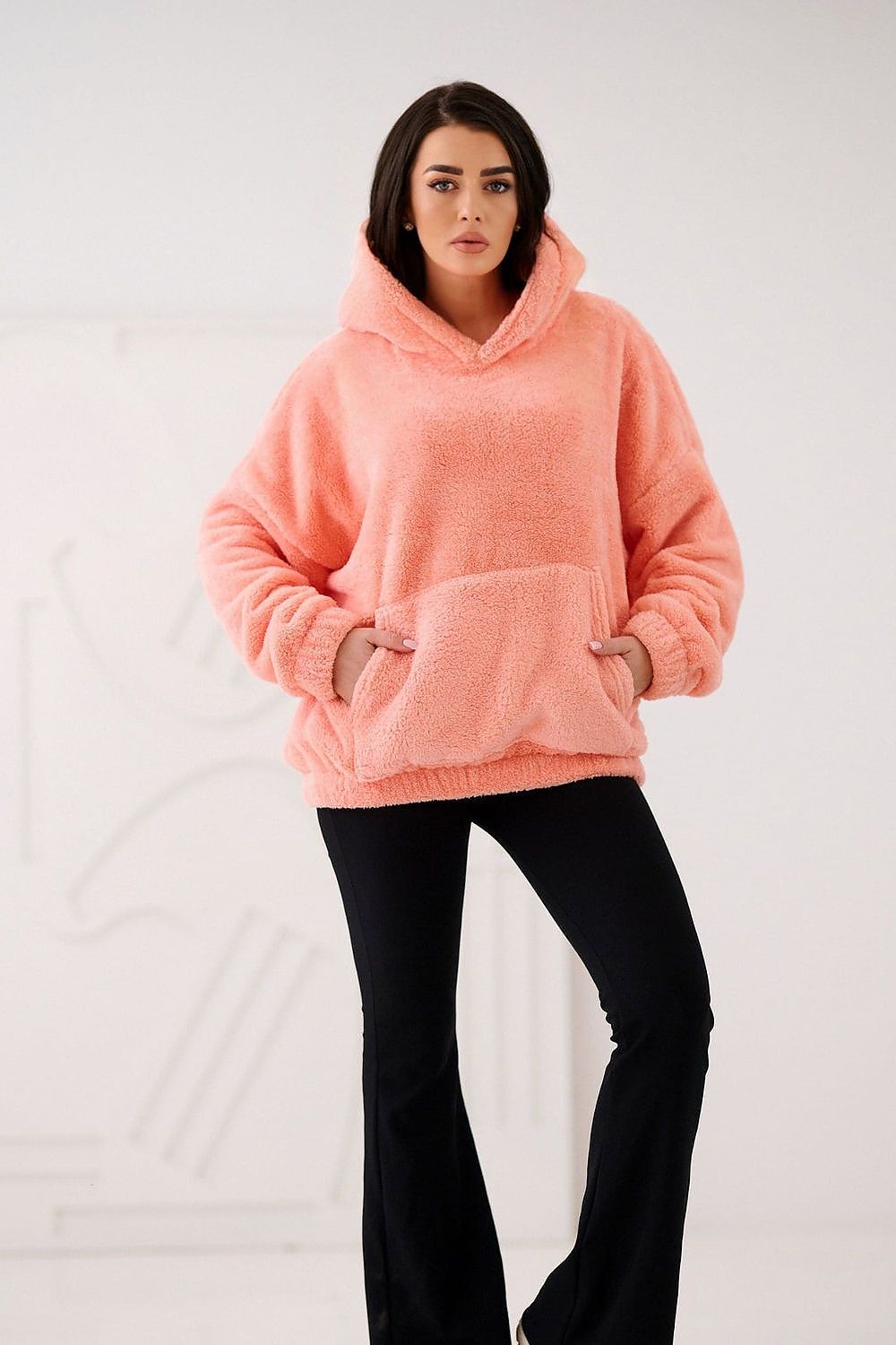 Woman wearing a pink hoodie and black pants on a white background
