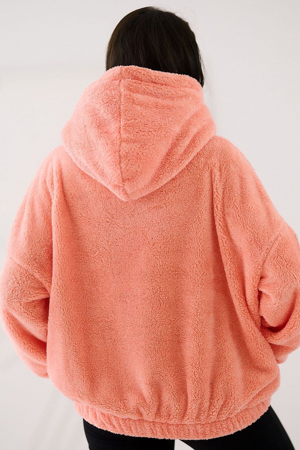 Person wearing a pink fleece hoodie on a white background