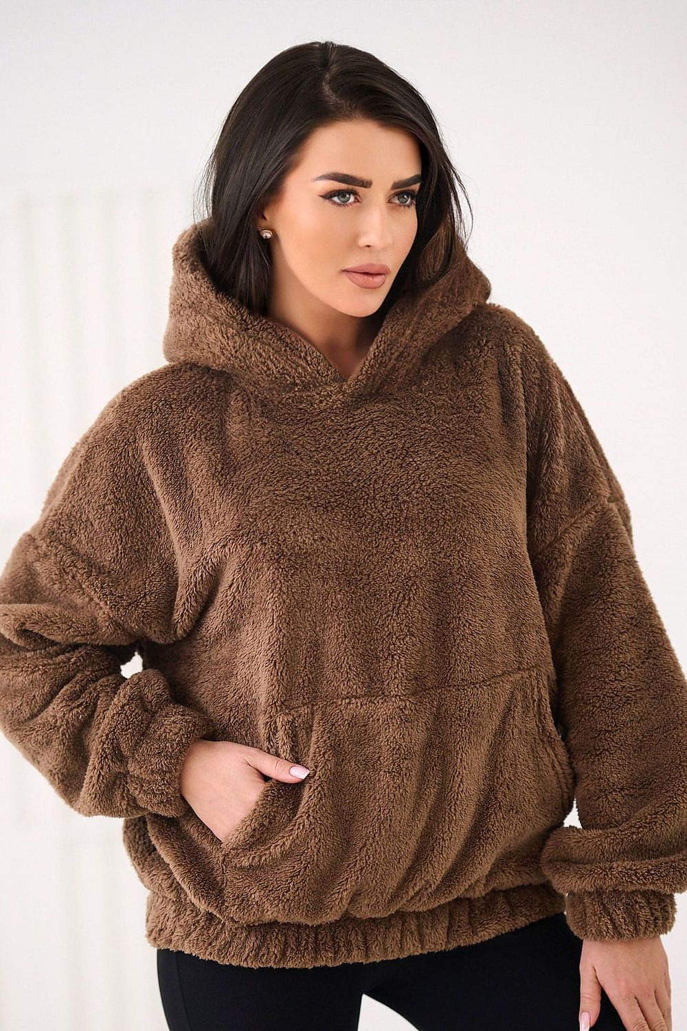 Woman wearing a brown fleece hoodie against a white background