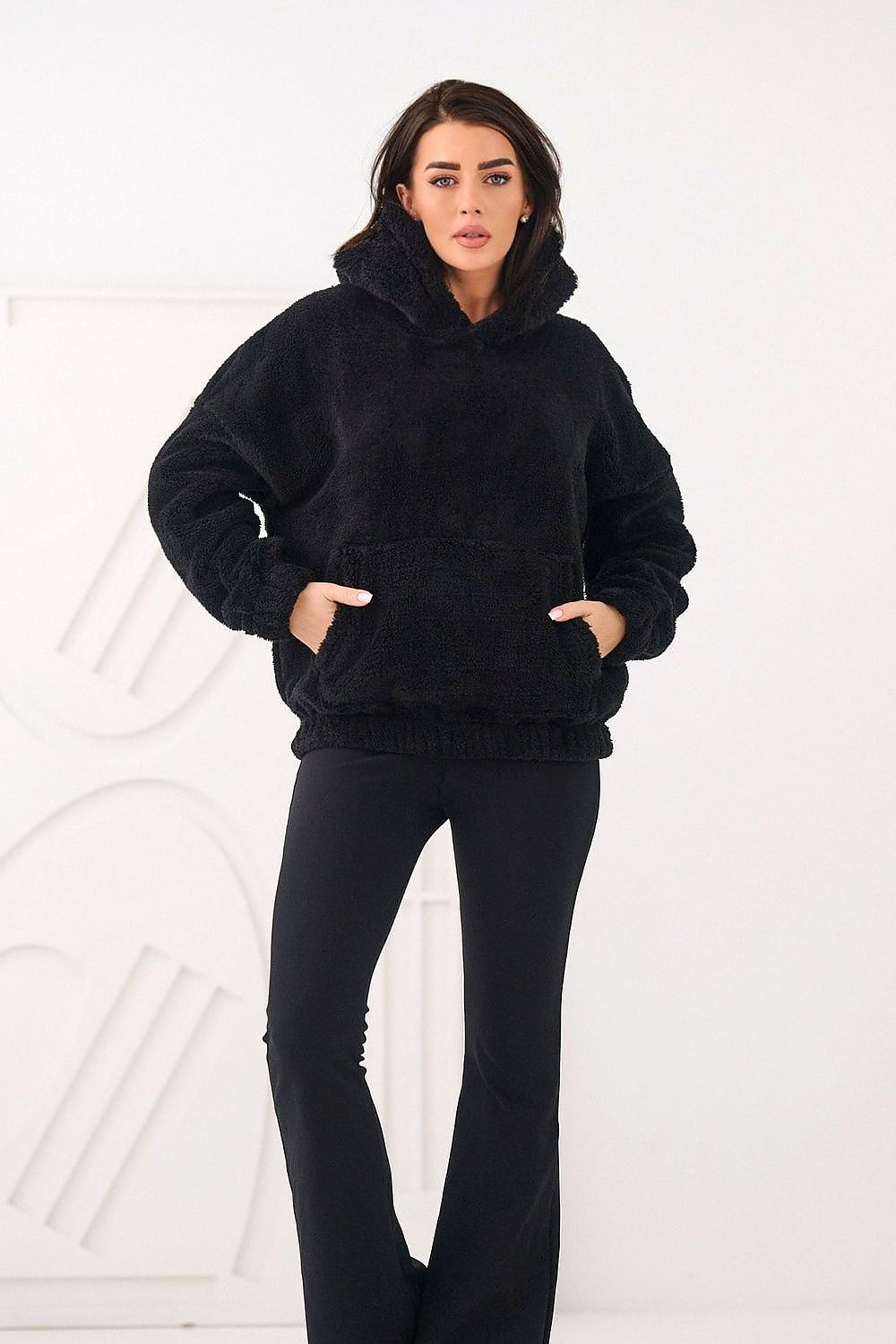 Person wearing a black hoodie and pants on a white background