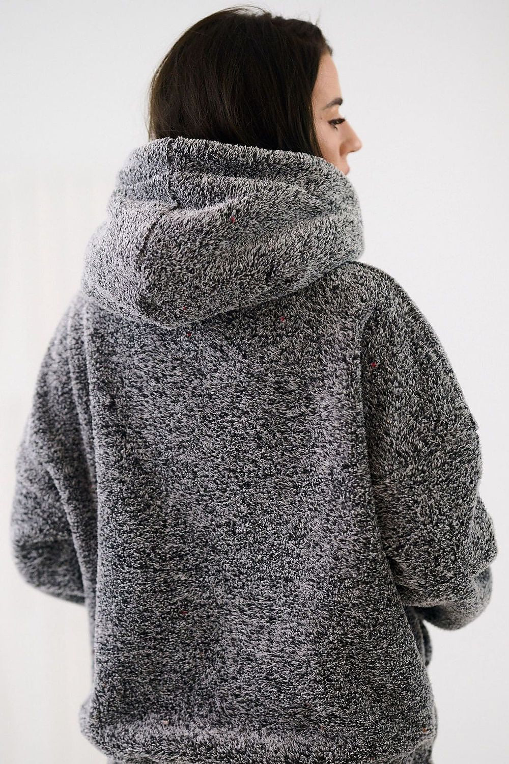 Person wearing a gray hooded jacket against a white background
