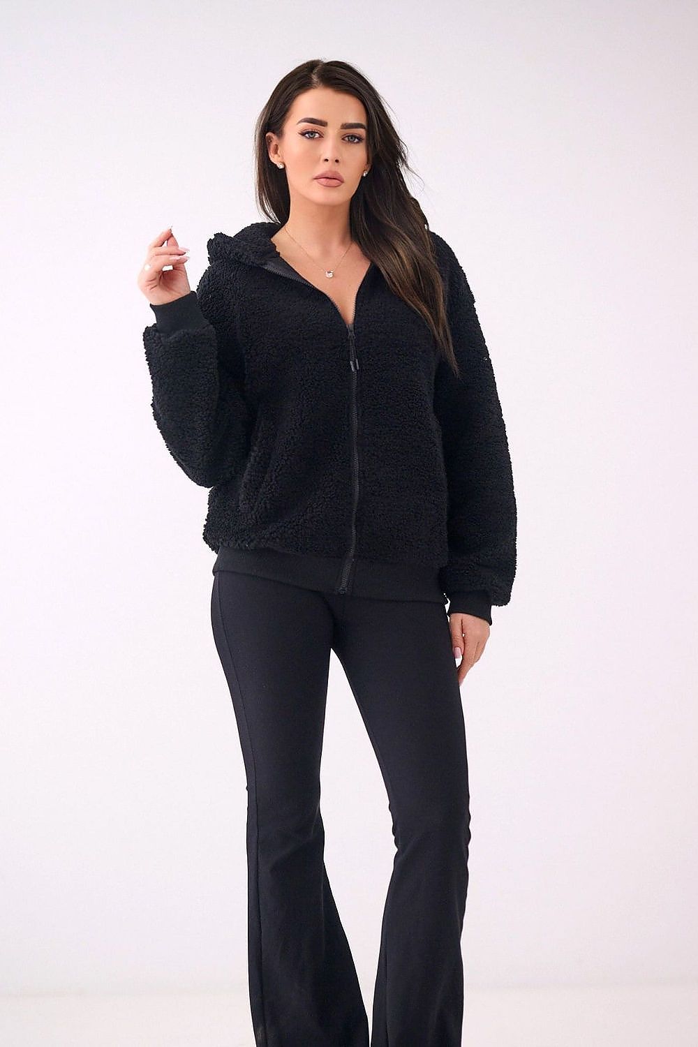 Woman wearing a black fleece jacket and pants on a white background