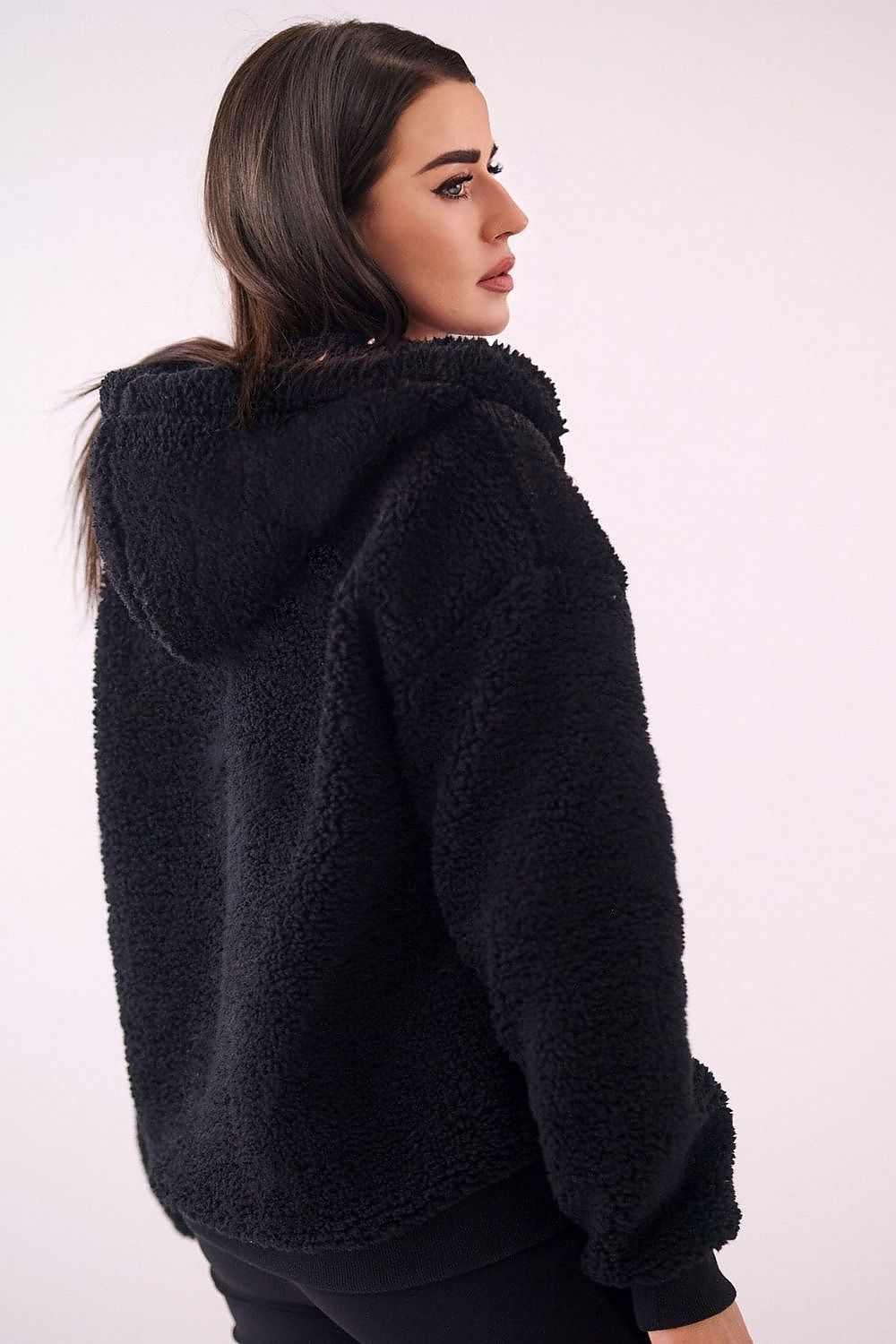 Woman wearing a black fluffy hoodie against a white background