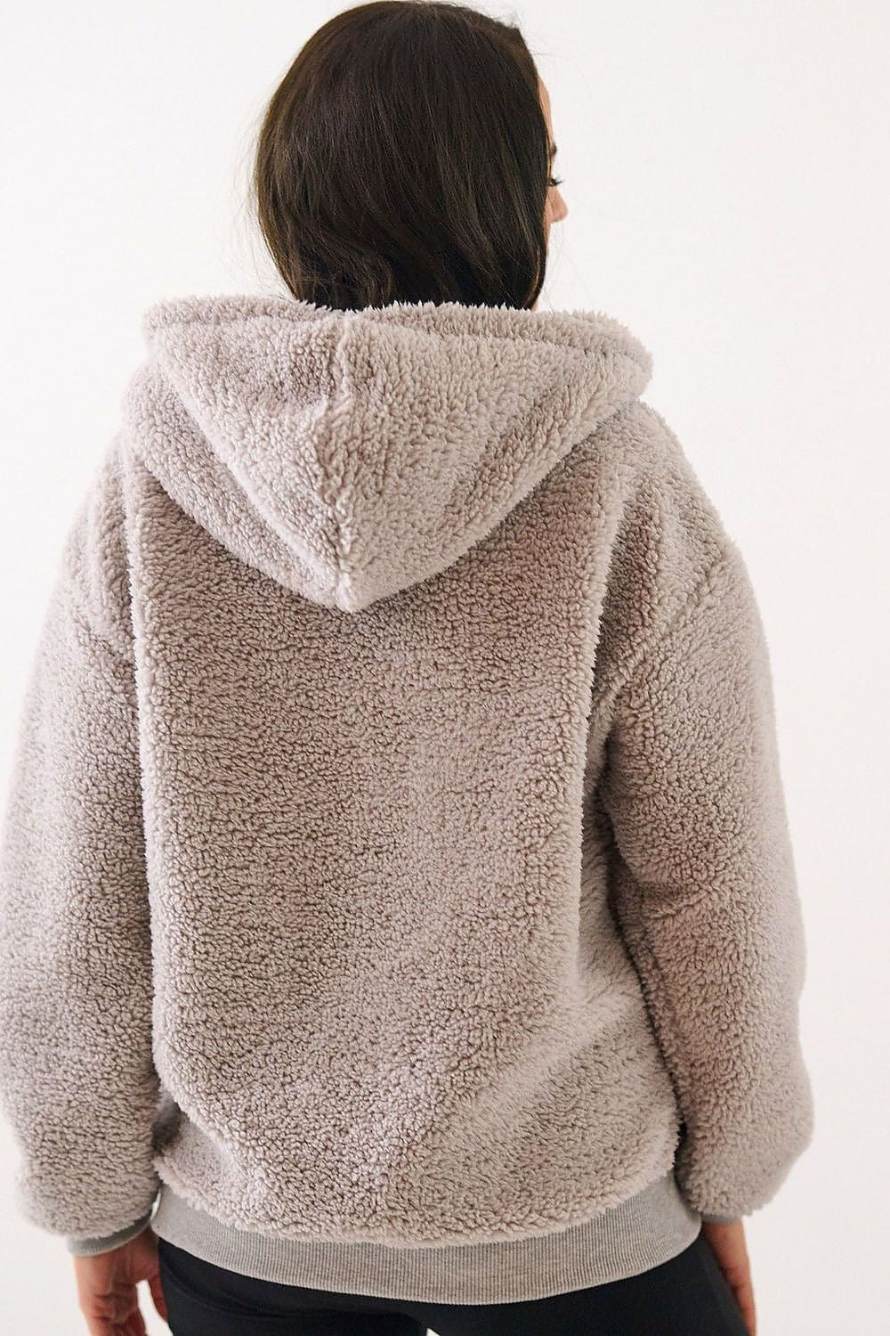 Person wearing a beige sherpa jacket on a white background