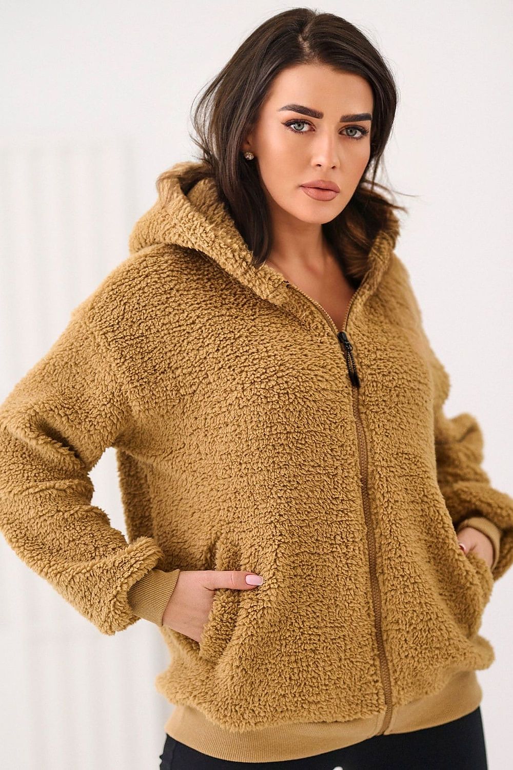Woman wearing a brown sherpa jacket against a white background