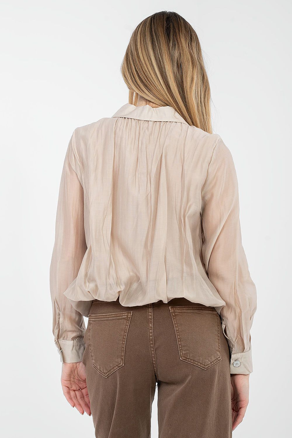 Woman wearing a beige blouse and brown pants on a white background