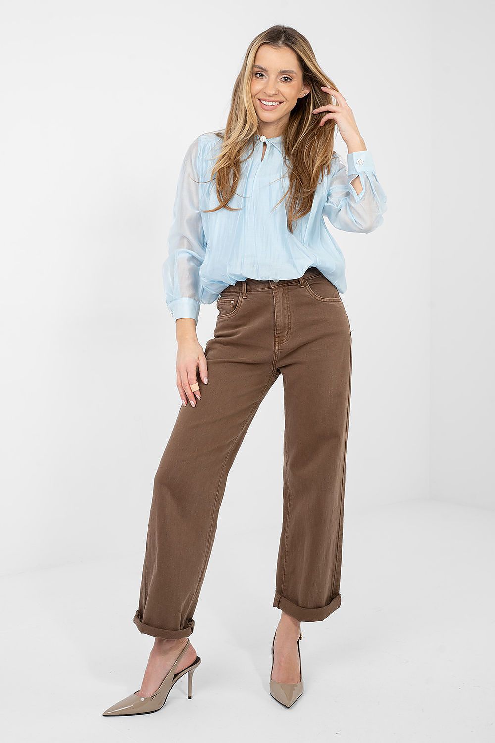 Woman wearing a light blue shirt and brown pants on a white background