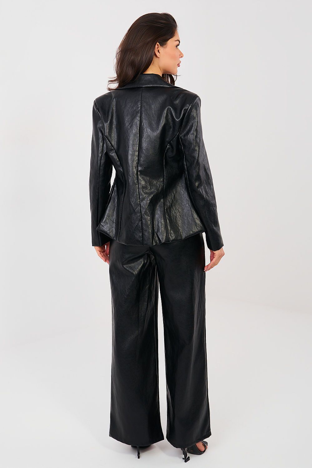 Woman wearing a black leather jacket and pants on a white background