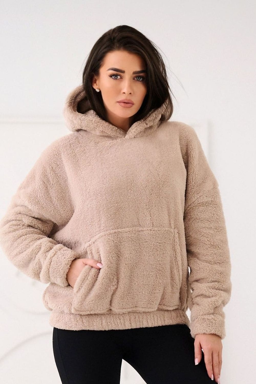 Woman wearing a beige fleece hoodie on a white background