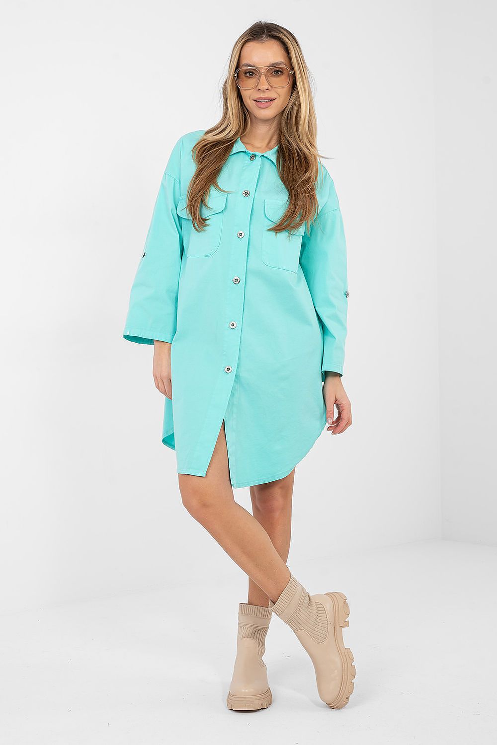 Woman wearing a turquoise dress with a white background