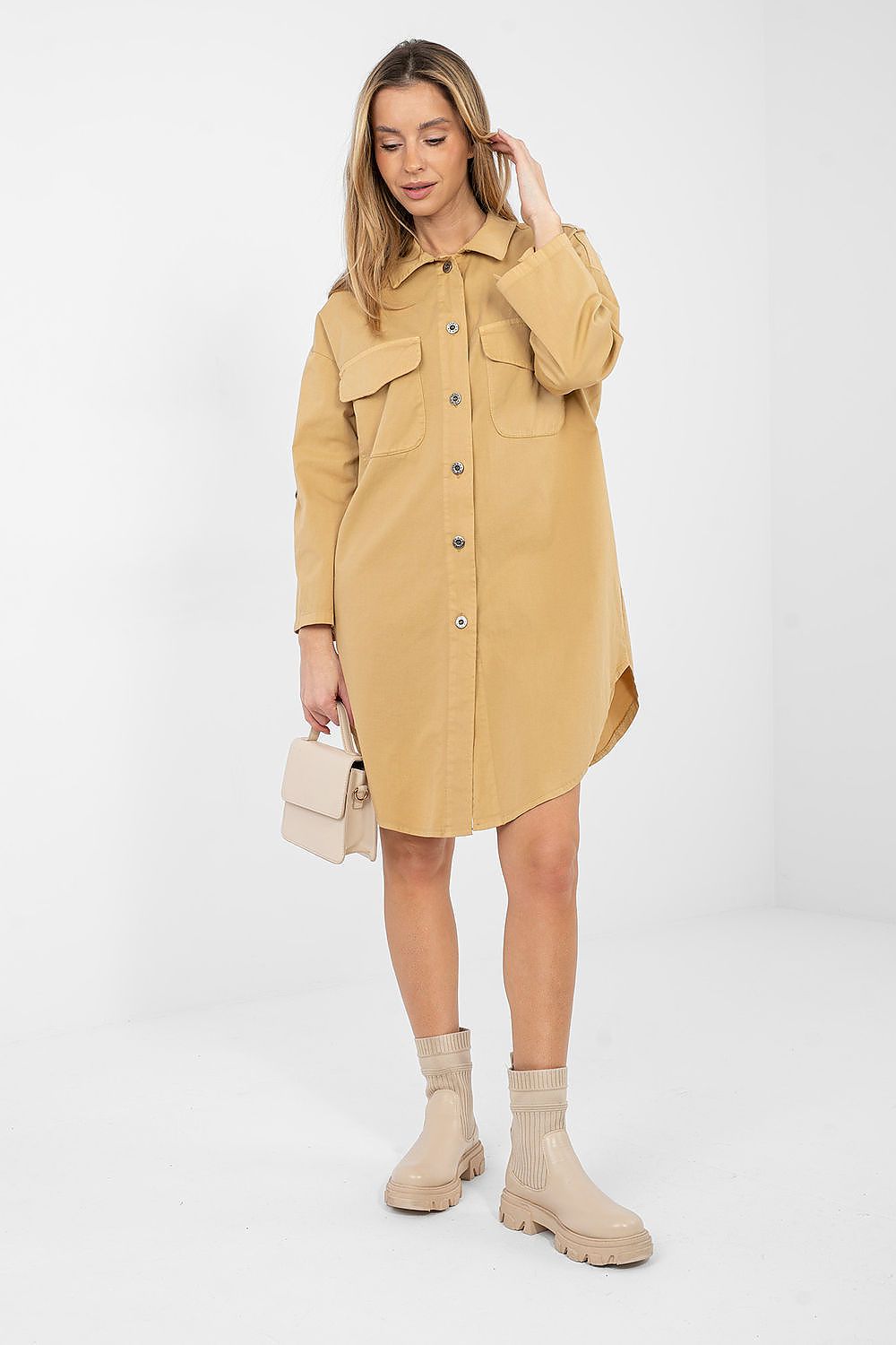 Woman wearing a beige shirt dress with beige boots on a white background