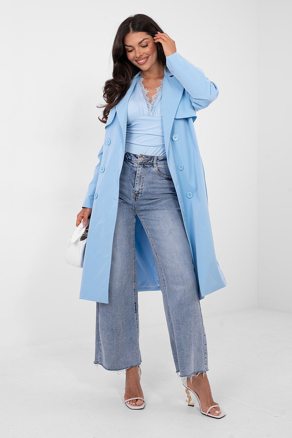Woman wearing a light blue coat and jeans on a white background