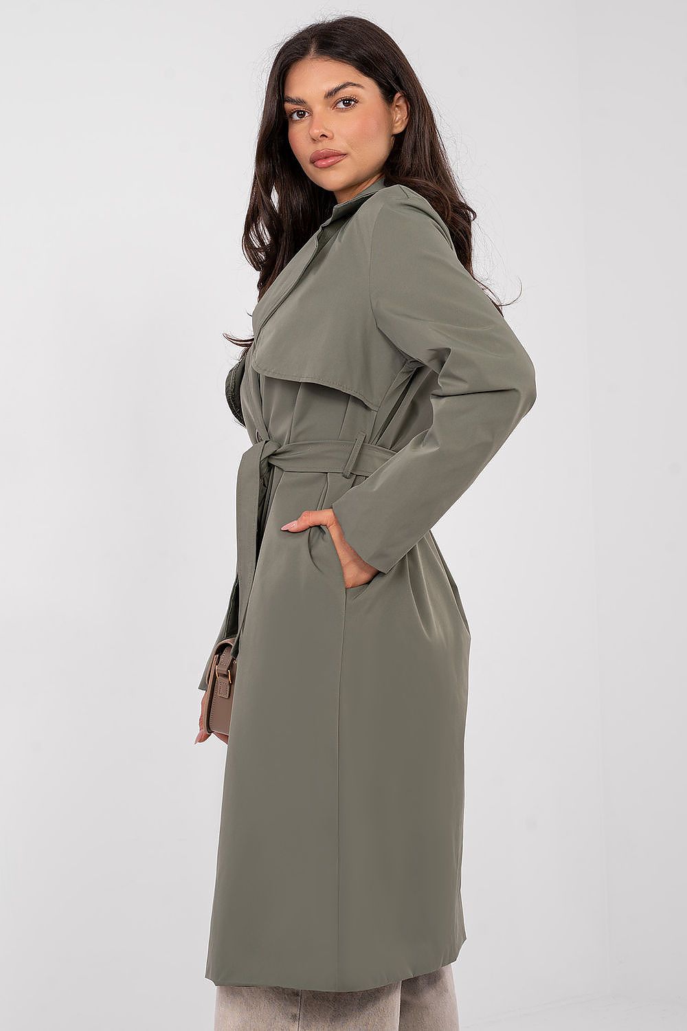 Woman wearing a green trench coat against a white background