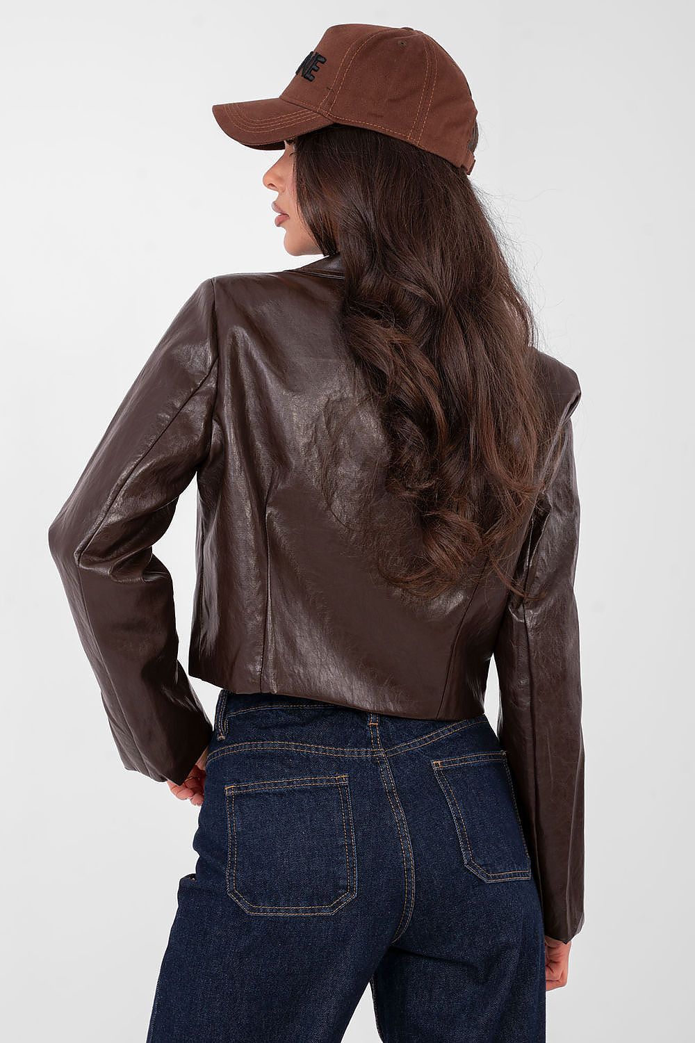 Person wearing a brown leather jacket and cap on a white background