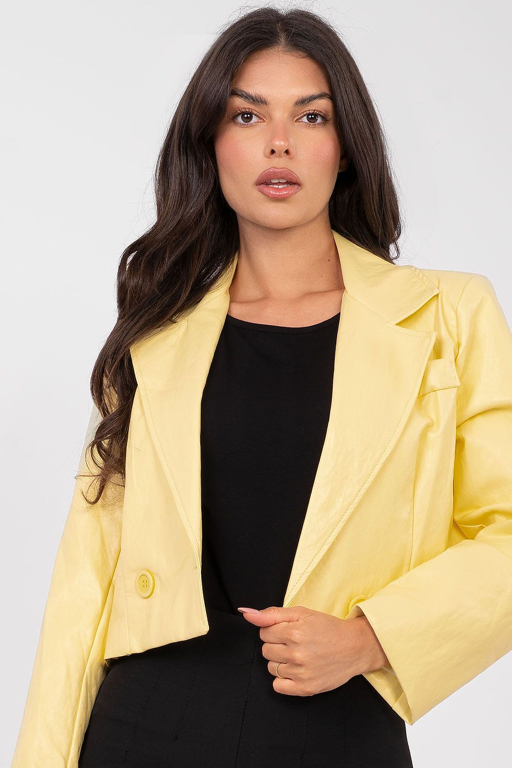 Woman wearing a yellow blazer over a black top on a white background