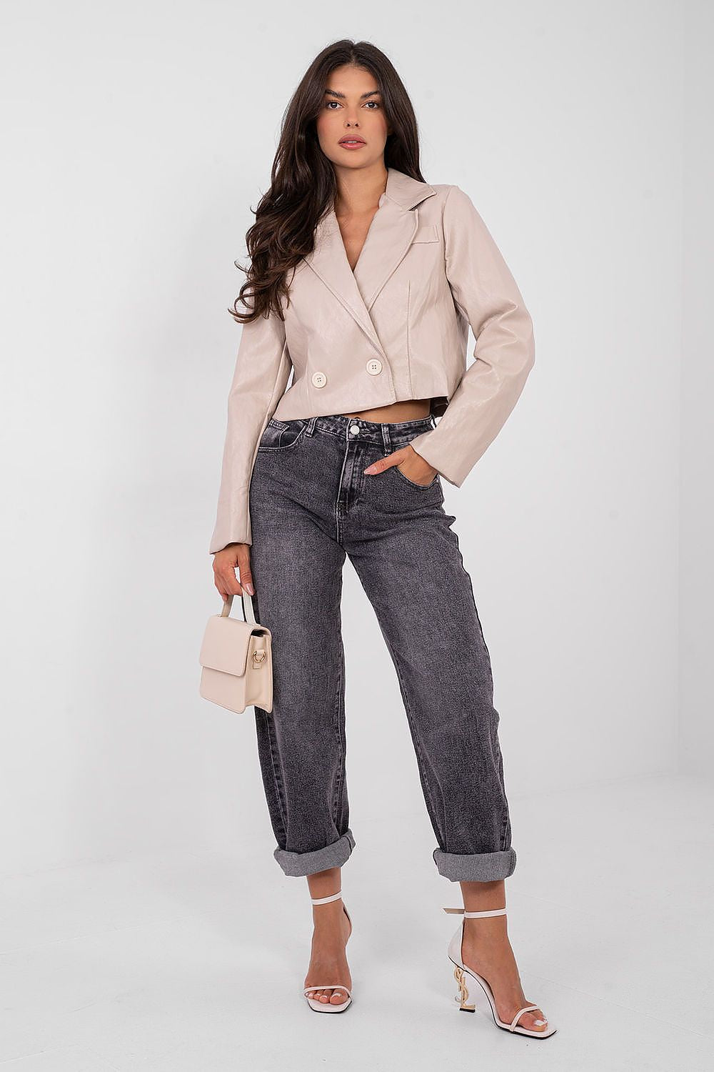 Woman wearing a beige blazer and black jeans on a white background