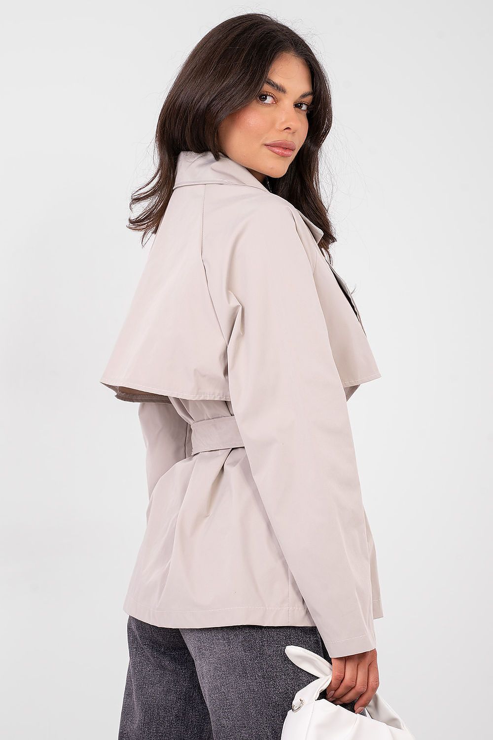 Woman wearing a beige trench coat on a white background