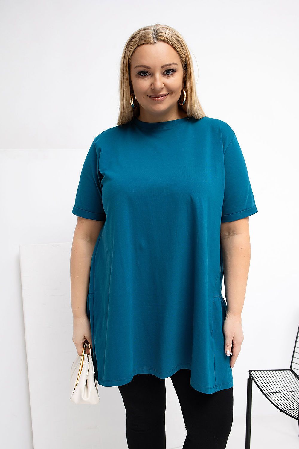 Woman wearing a teal tunic over black leggings on a white background
