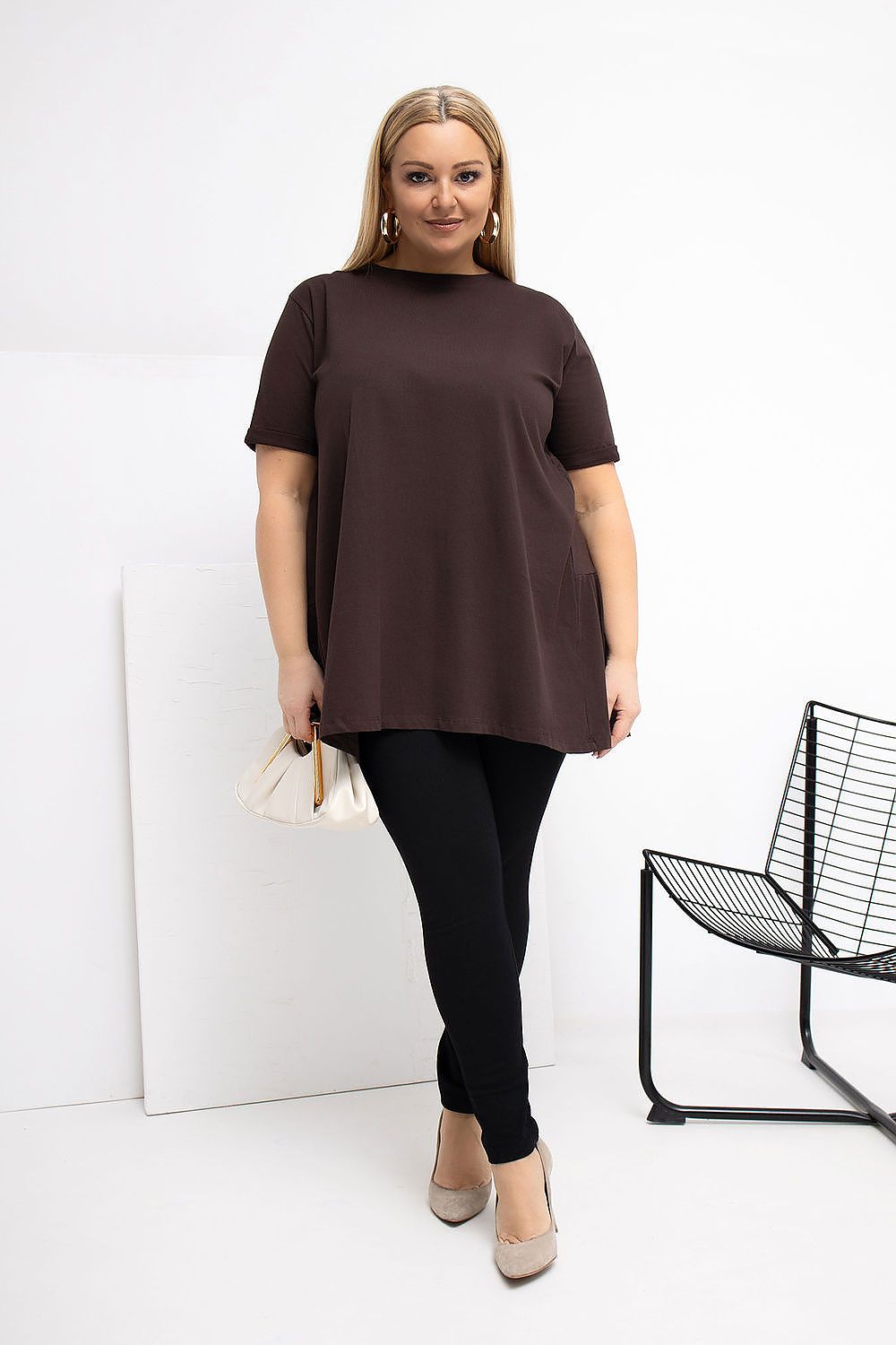 Woman wearing a brown tunic and black leggings against a white background