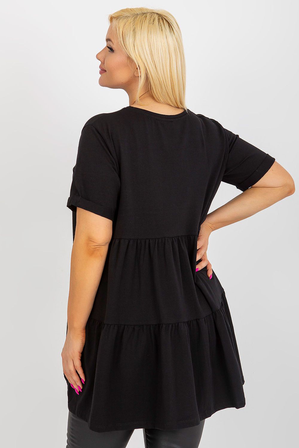 Woman wearing a black dress with a layered skirt on a plain background