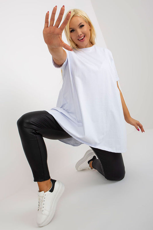 Person wearing a white oversized t-shirt and black pants on a plain background