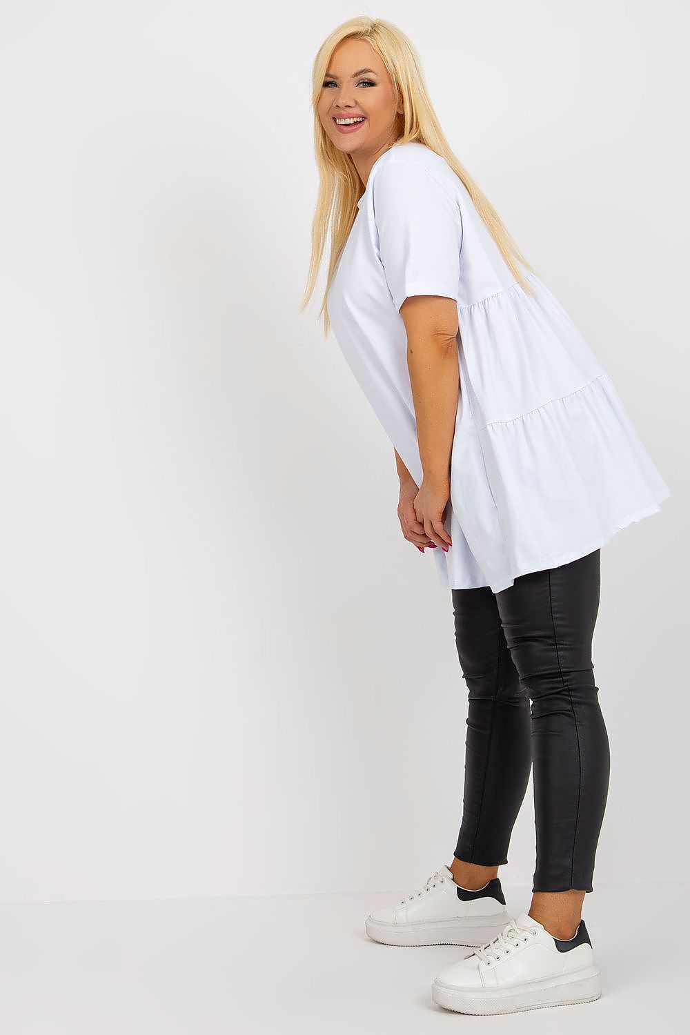 Woman wearing a white tunic and black pants on a white background