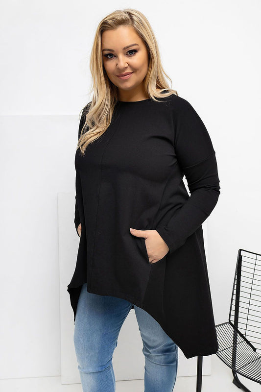 Woman wearing a black long-sleeve top and blue jeans against a white background