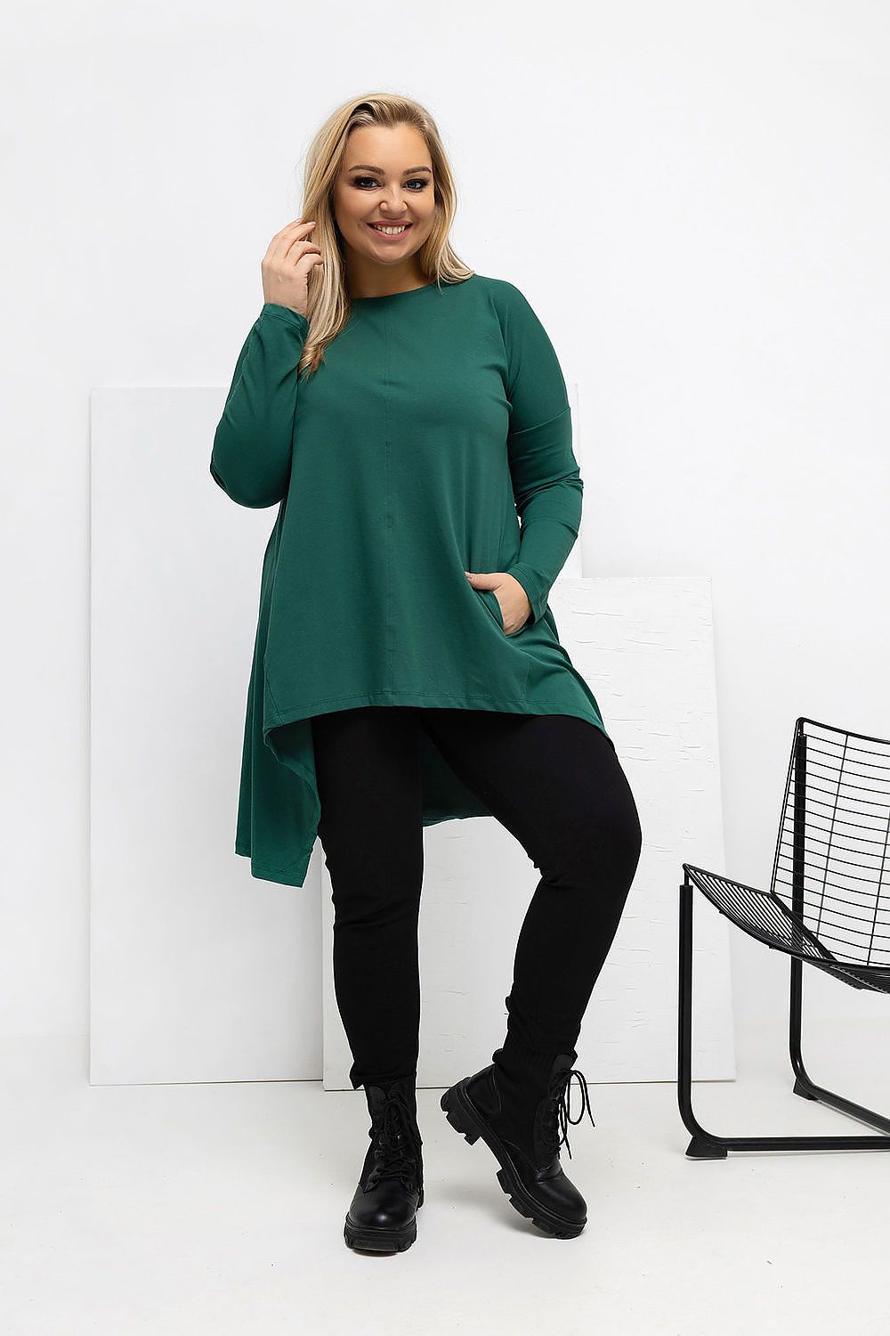 Woman wearing a green dress and black leggings against a white background