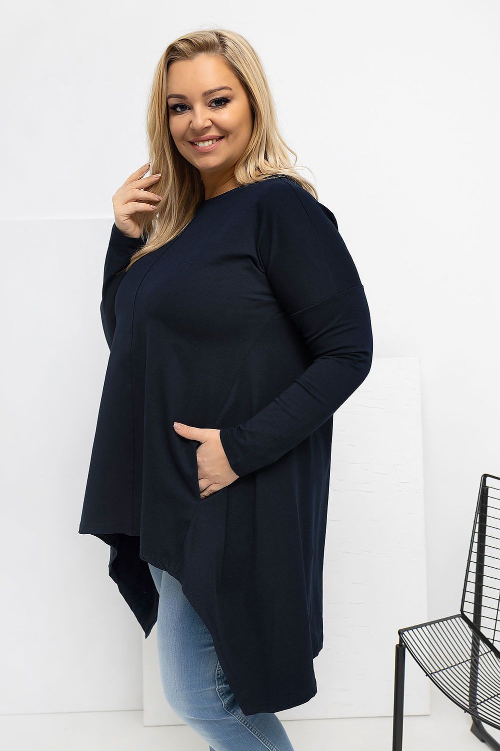 Woman wearing a navy blue cardigan over a black top with light blue jeans on a white background