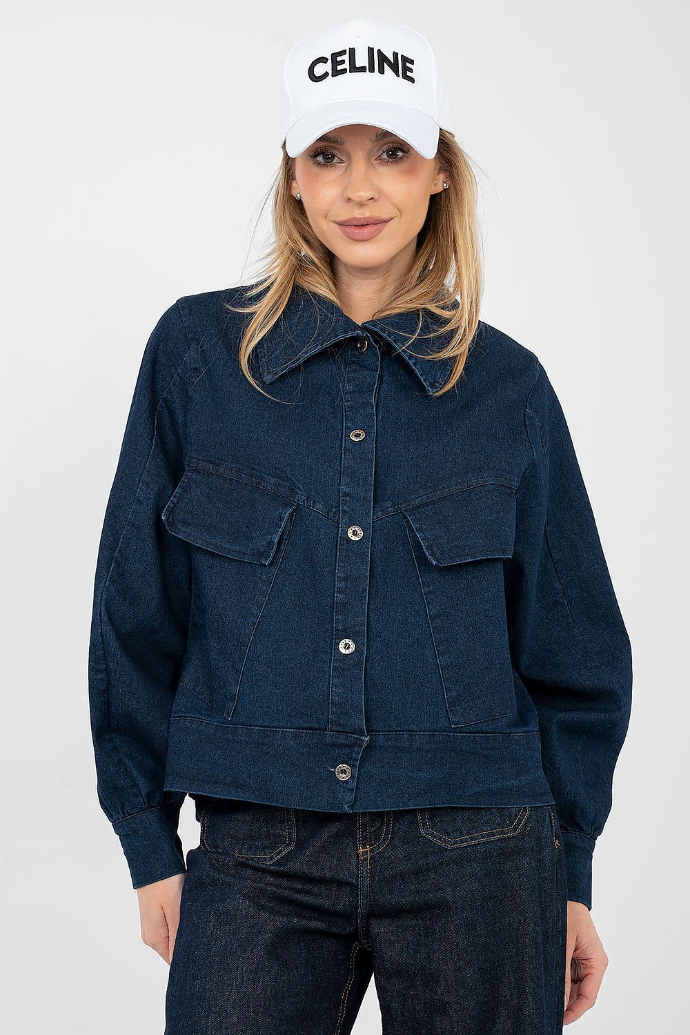 Person wearing a navy denim jacket and white Celine cap on a white background