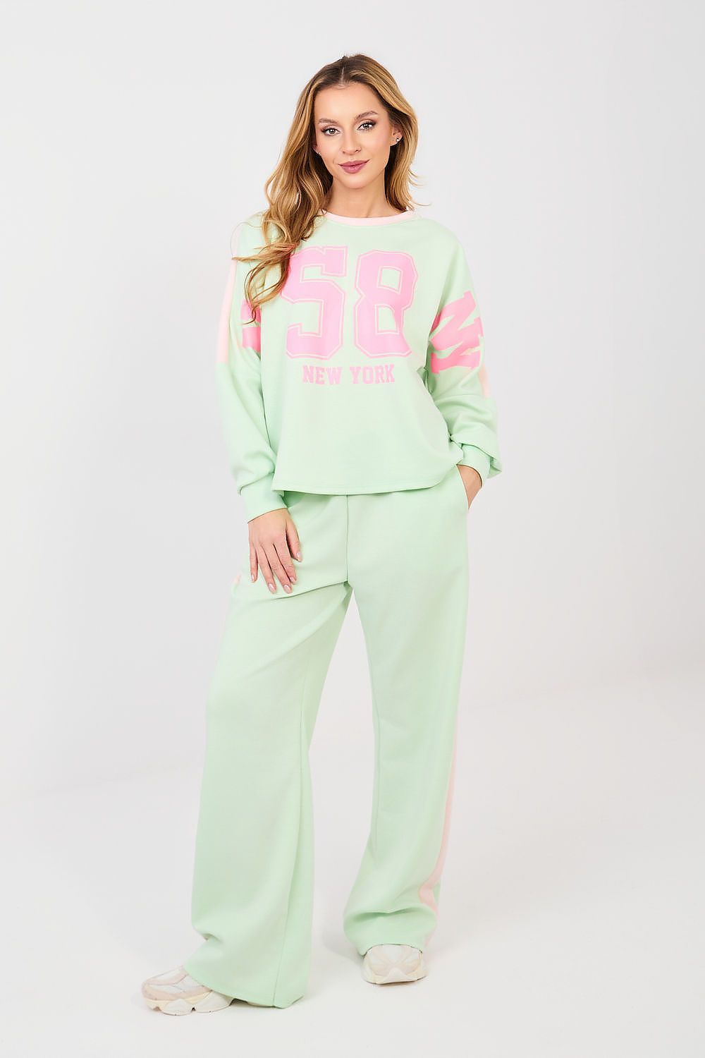 Woman wearing a light green tracksuit with pink text on a white background