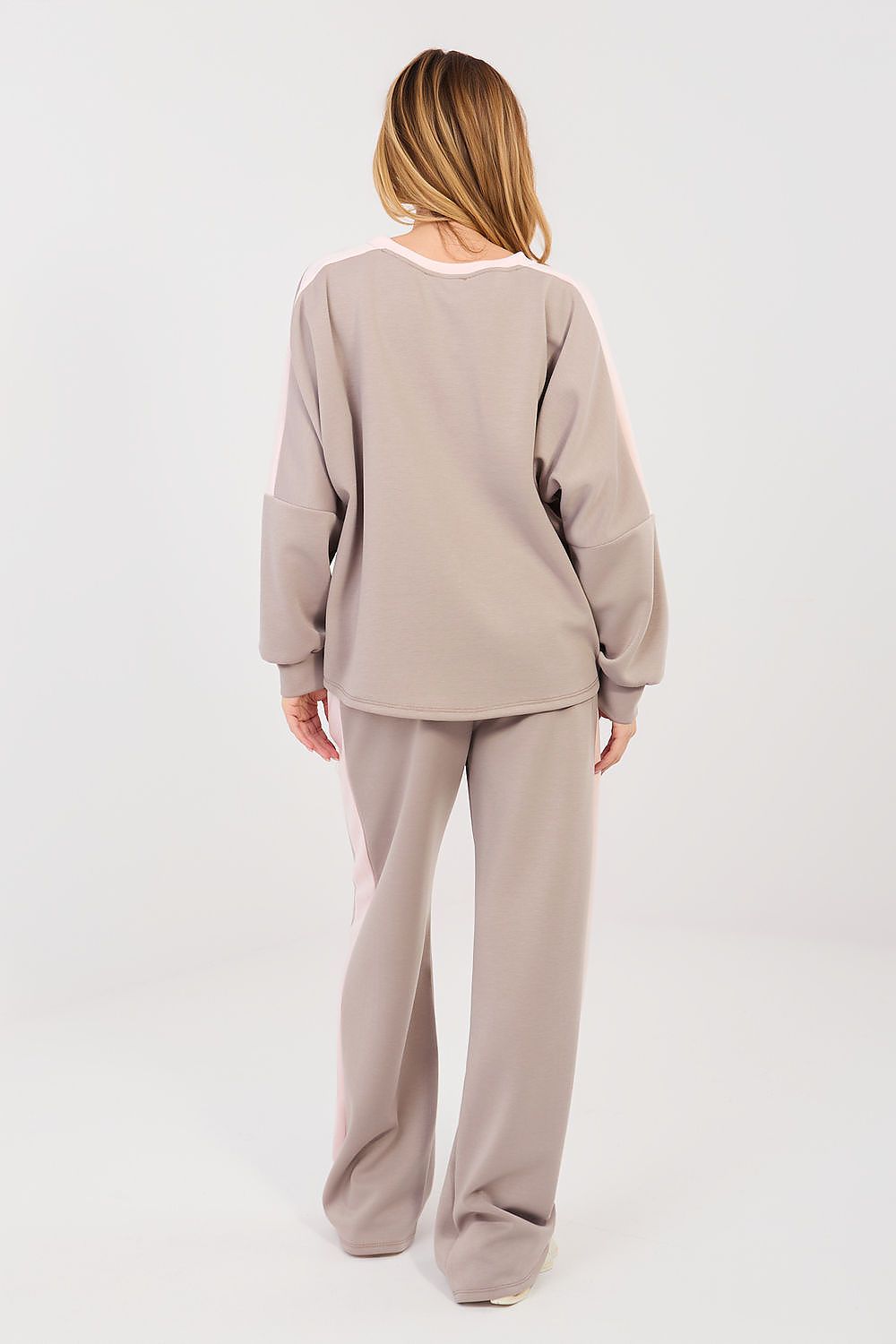 Person wearing a beige lounge set on a white background