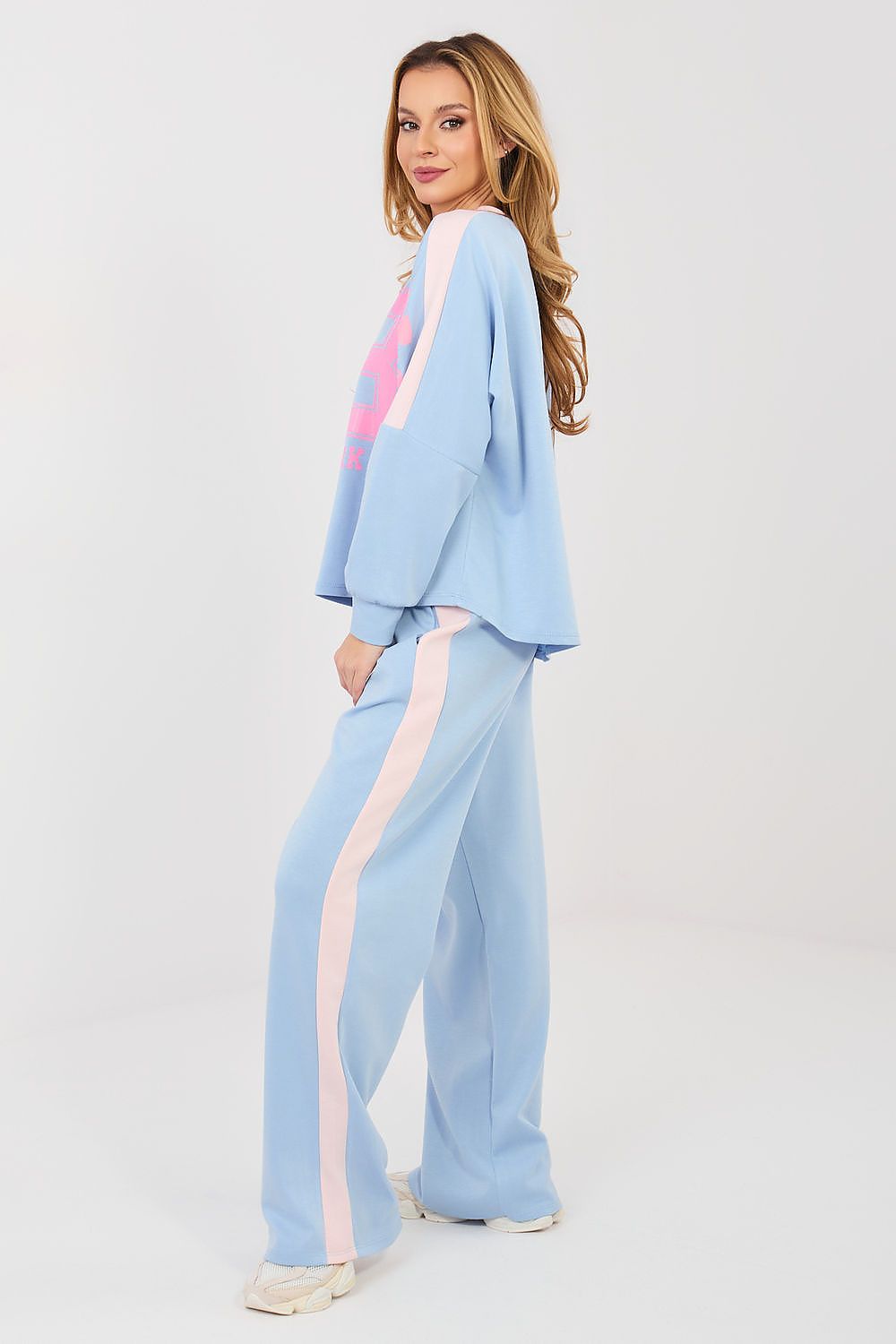 Woman wearing a light blue outfit with a pink top on a white background