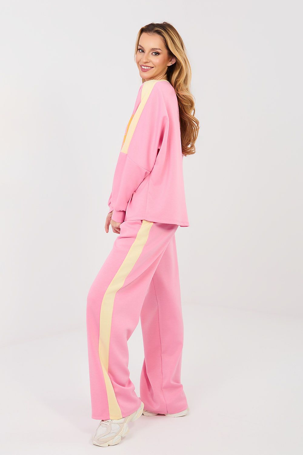 Woman wearing a pink tracksuit with yellow stripes on a white background