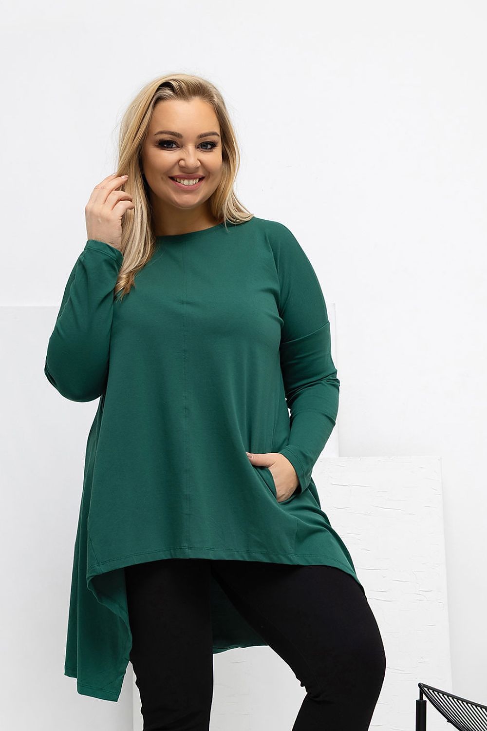Woman wearing a green long-sleeve top against a white background