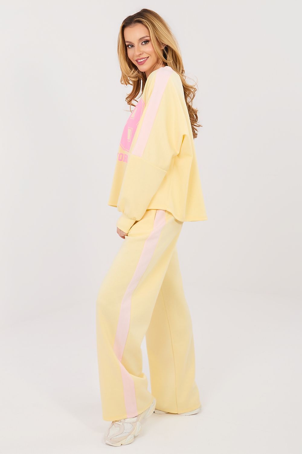 Woman wearing a yellow outfit with pink accents on a white background