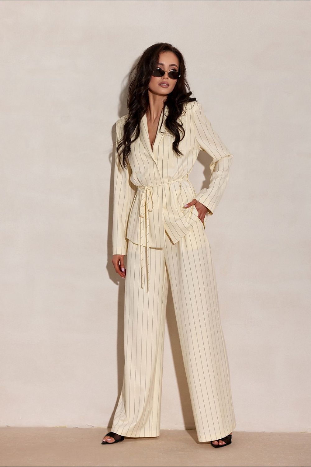 Woman wearing a cream pinstripe suit against a plain background