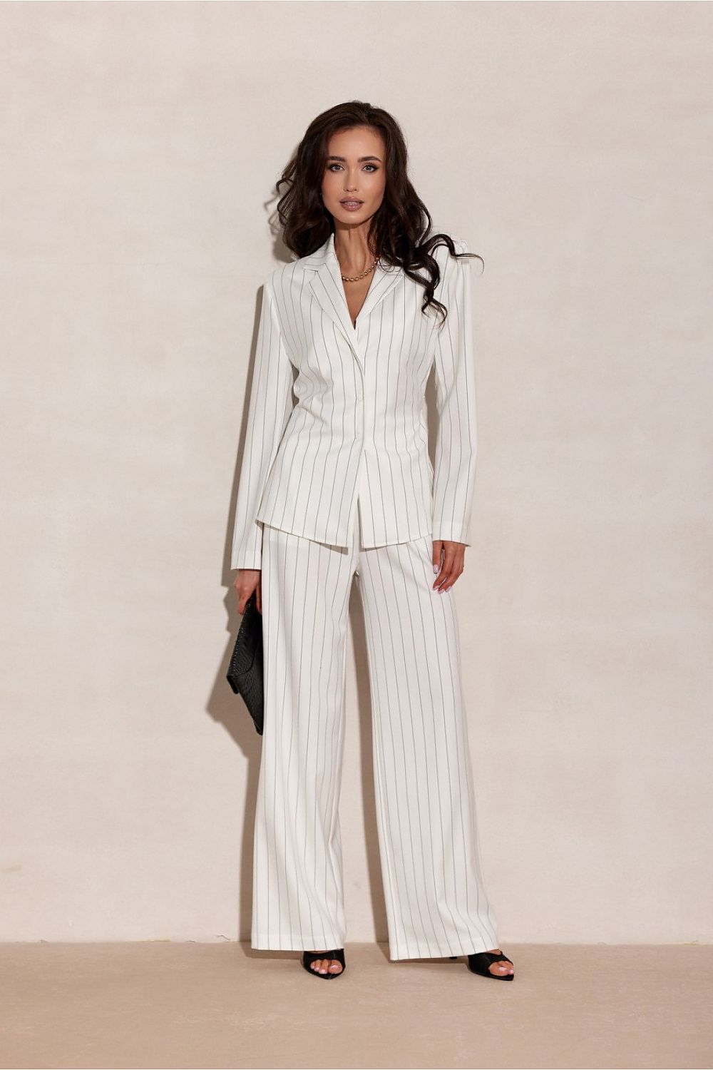 Woman wearing a white pinstripe suit against a beige background