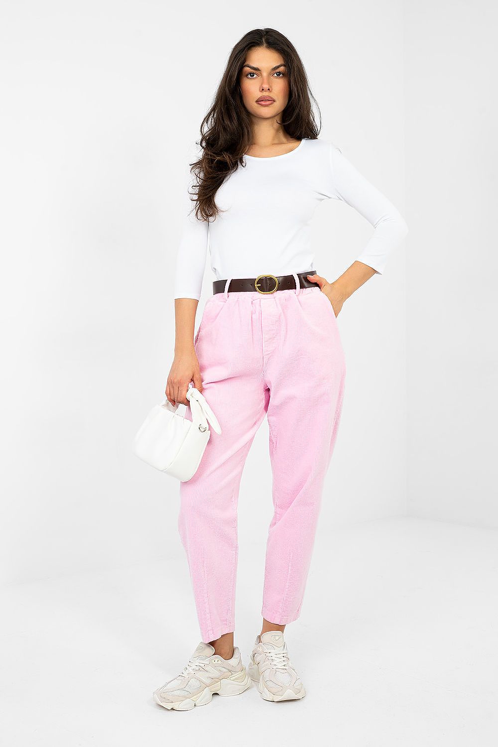 Woman wearing a white top and pink pants with a white background