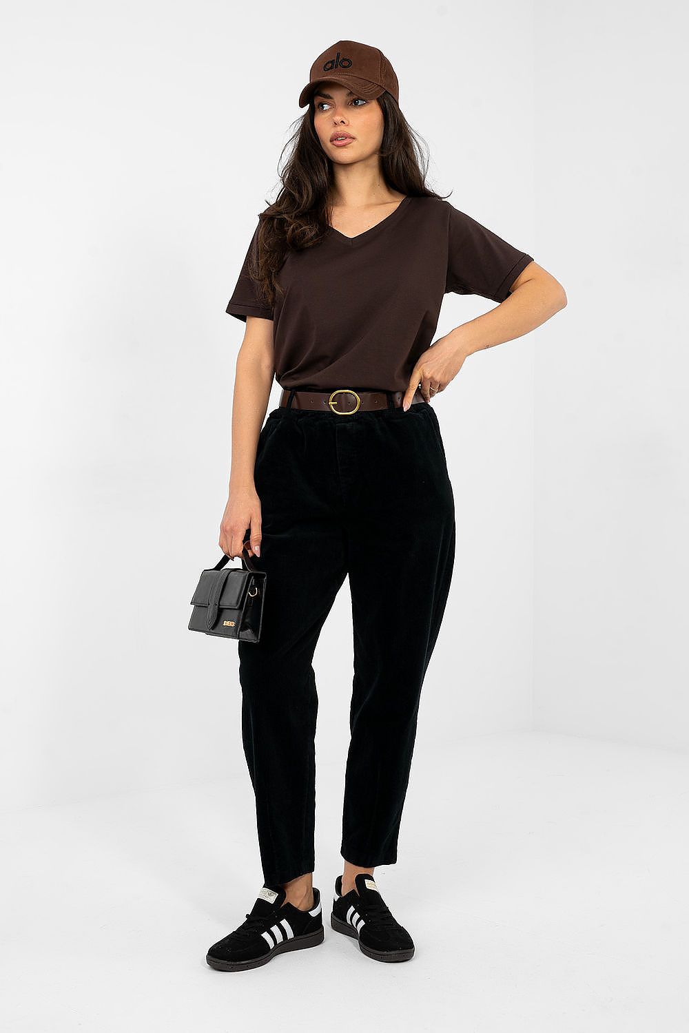 Woman wearing a brown t-shirt, black pants, and a cap on a white background