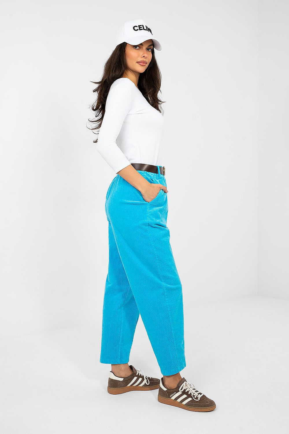 Woman wearing a white top, blue pants, and a cap on a white background