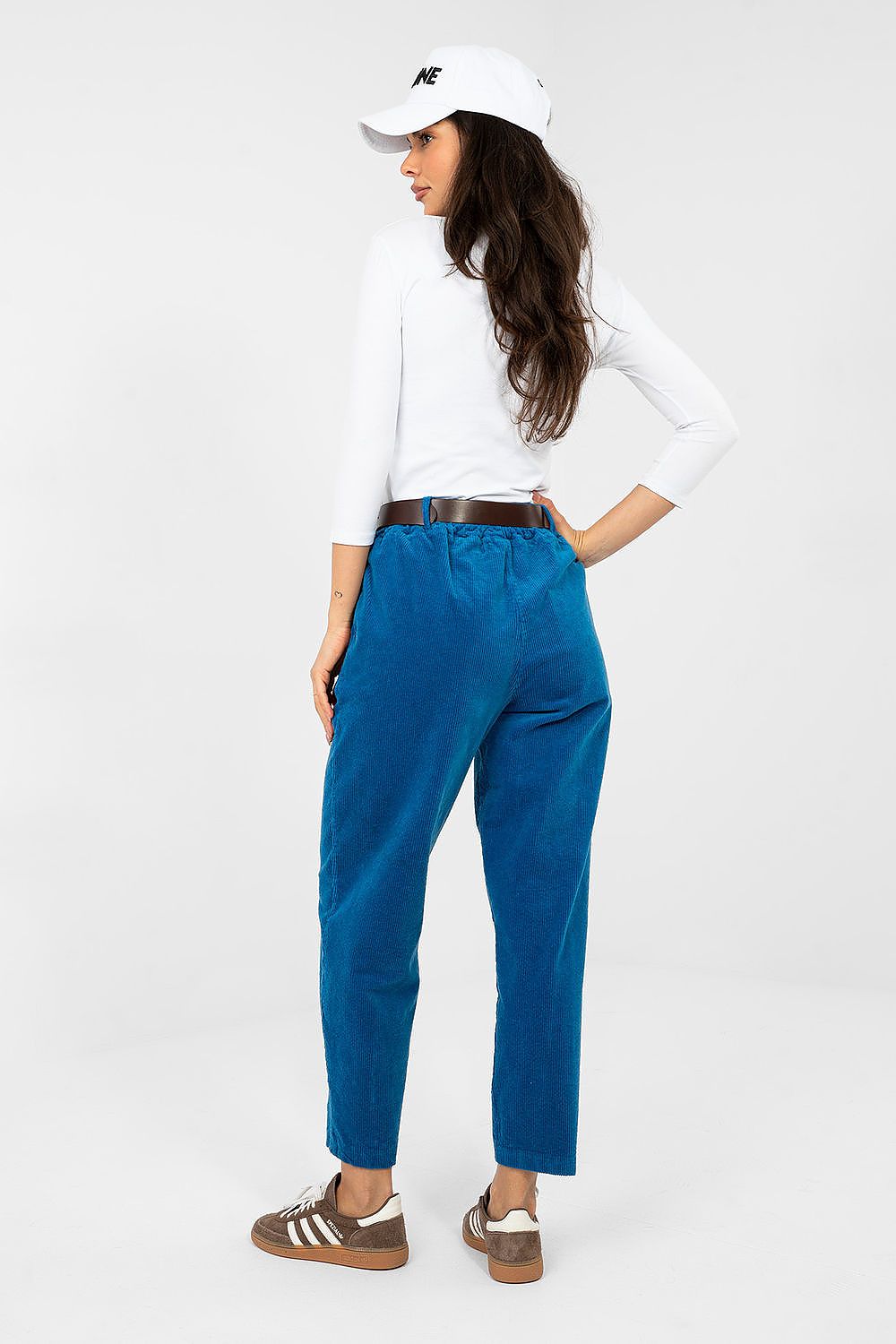 Woman wearing blue pants and a white shirt on a white background