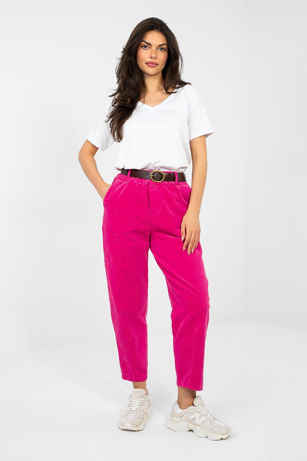 Woman wearing a white top and bright pink pants on a white background