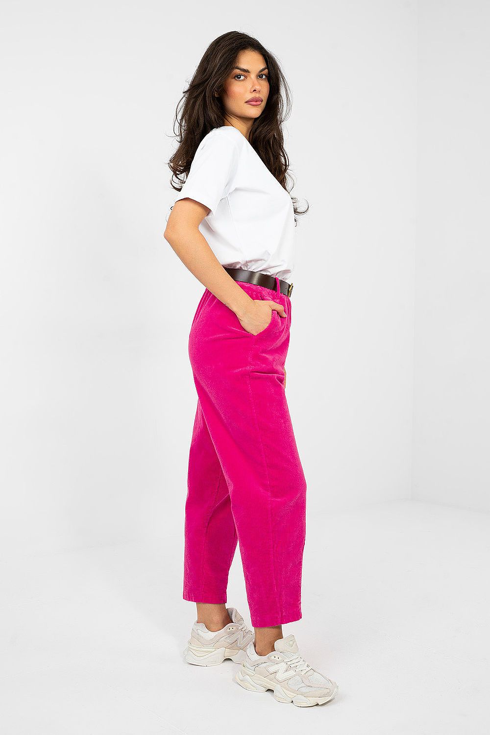 Woman wearing a white top and bright pink pants on a white background