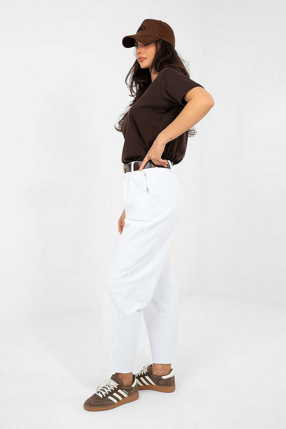 Person wearing a brown cap, dark shirt, white pants, and brown shoes on a white background