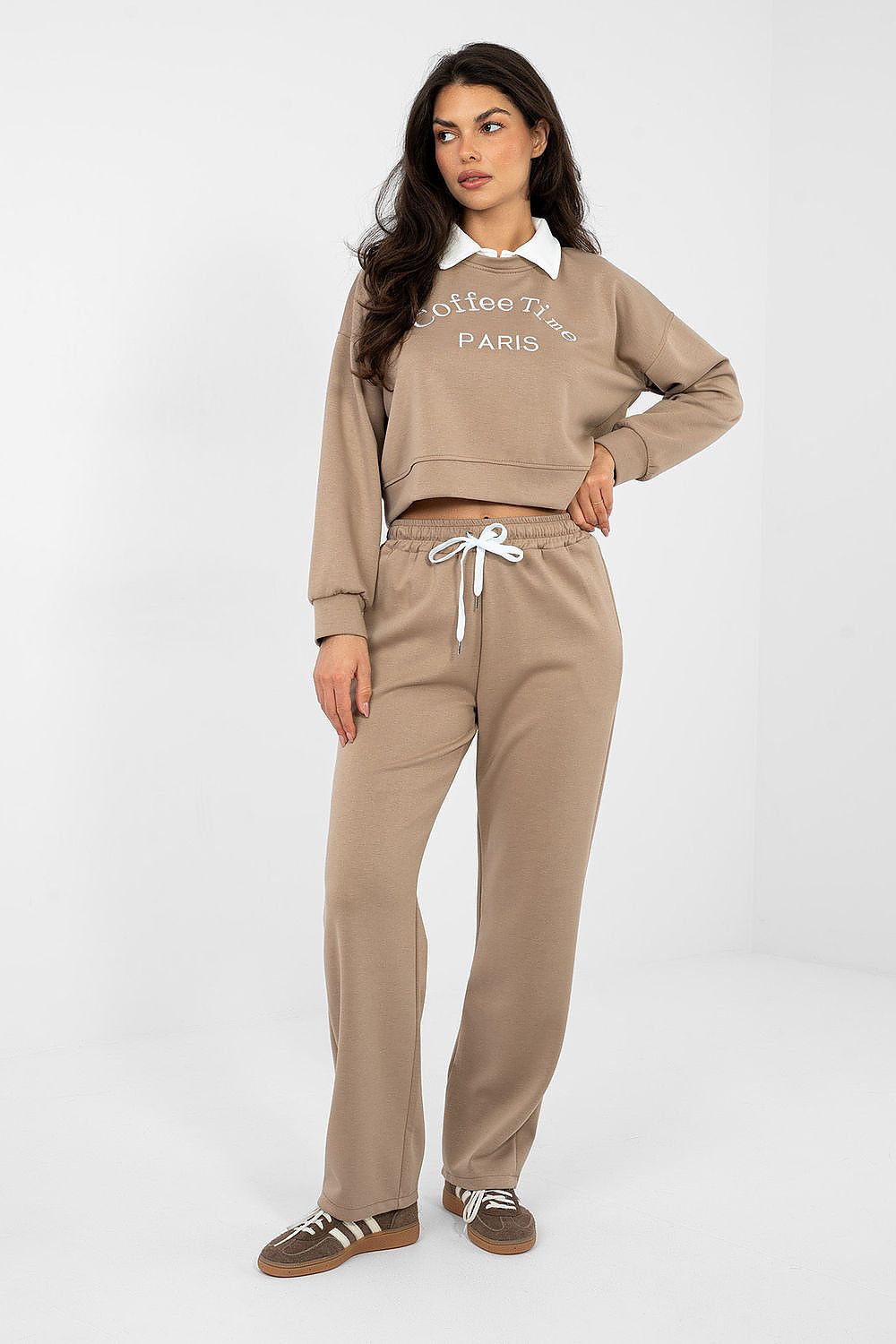 Woman wearing a beige tracksuit with 'Paris' text on a white background