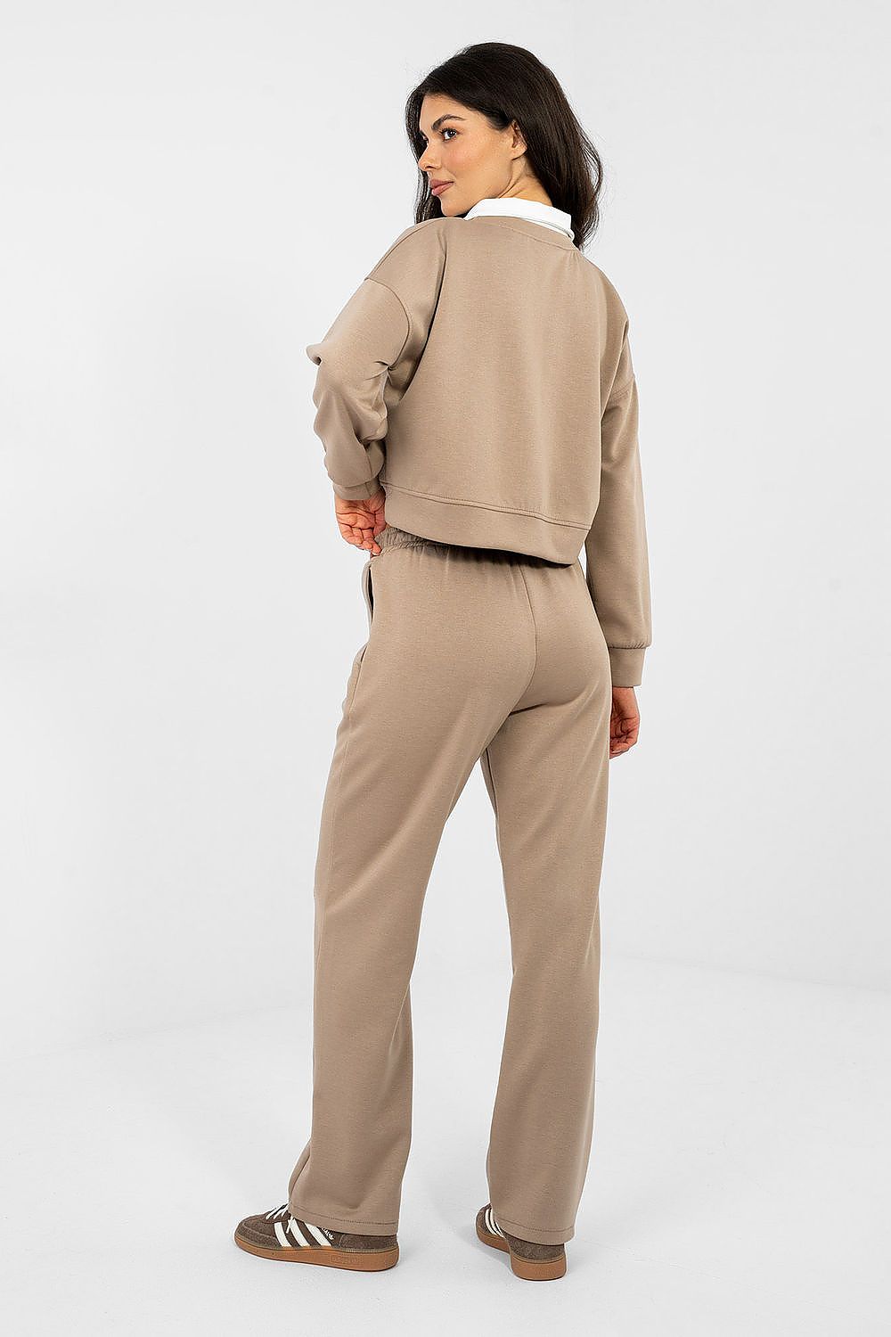 Woman wearing a beige tracksuit on a white background