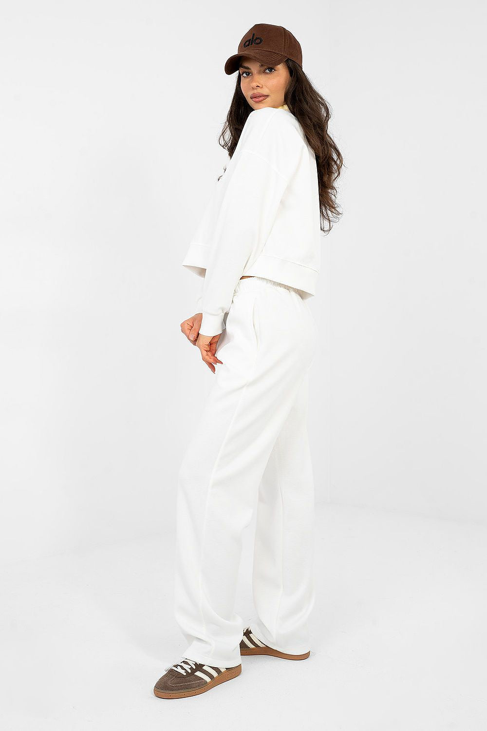 Woman wearing a white outfit with a brown cap on a white background