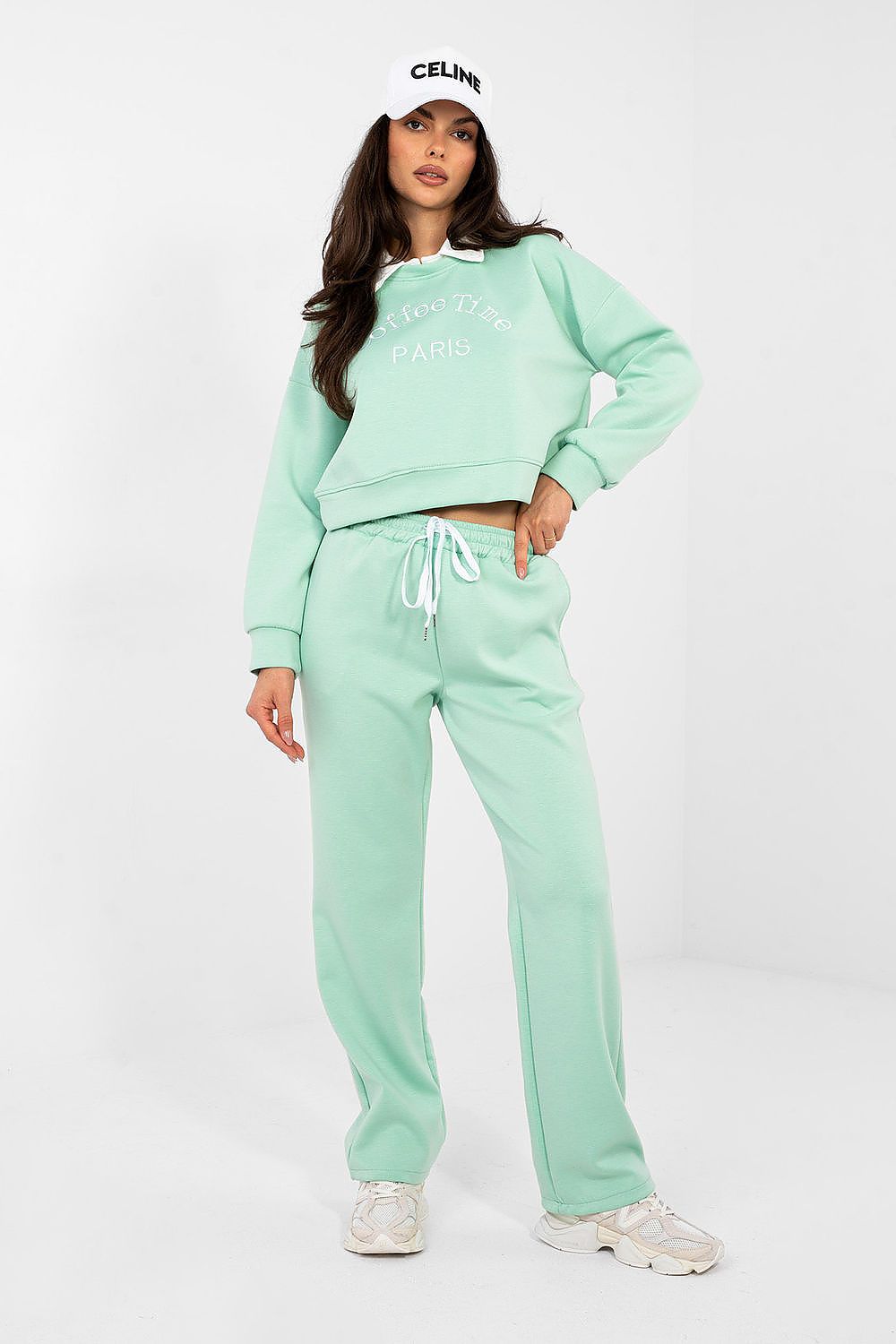 Person wearing a mint green Celine tracksuit on a white background